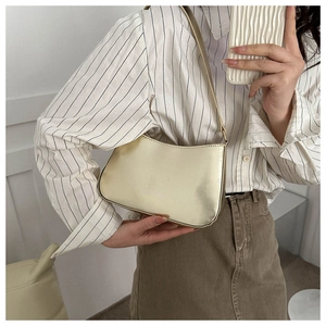 Detail shot of pale gold metallic shoulder bag styled with a striped shirt on model