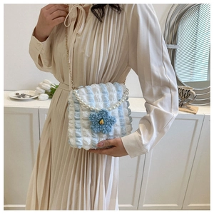 Detail of blue and white bubble texture tote bag with pearl handle and plush flower