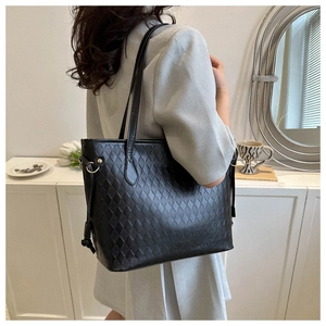 Close-up of black quilted large tote bag showing textured diamond pattern and shoulder straps