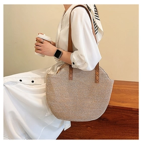 Detail of hand-woven straw tote with premium brown leather straps and cross-stitch detail