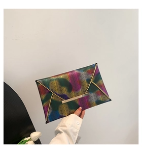 Detailansicht einer regenbogenfarbenen Umschlagtasche mit Wellenmuster und goldener Metallleiste