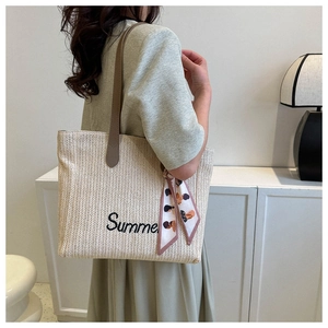 Détail d'un grand sac cabas en paille avec broderie Summer et anses en cuir sur l'épaule