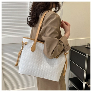 Detail of white tote bag with diamond quilted texture, brown trim and side drawstrings