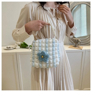 Detailed macro view of the pearl handle and blue knit flower on bubble tote bag