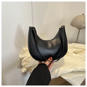 Close-up of black crocodile-embossed leather half-moon shoulder bag with sleek zip
