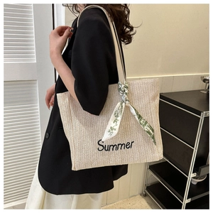 Détail du sac cabas en paille crème avec broderie Summer et foulard en soie sur la hanse