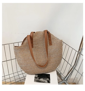 Detail of hand-woven straw tote bag with reinforced brown PU leather handles for summer