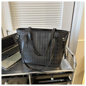 Detail of black quilted tote bag with drawstring side and gold-tone metal hardware