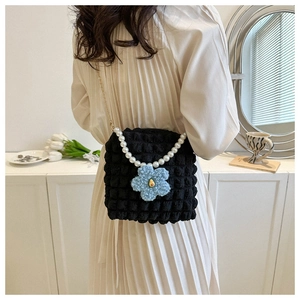 Detail of black popcorn texture bag featuring a pearl strap and plush flower charm
