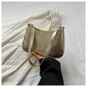 Detail of metallic gold shoulder bag with Fashion & Bags text on white textured bedding