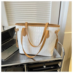 Macro shot of white tote bag with quilted diamond pattern and caramel brown leather straps