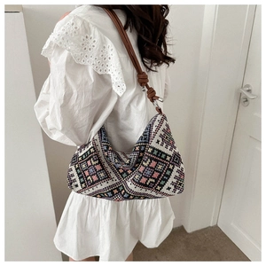 Close-up of bohemian woven hobo bag featuring colorful geometric patterns and knotted strap