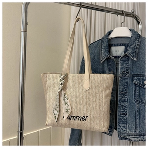 Détail d'un sac cabas en paille d'été avec broderie et décoration de foulard floral
