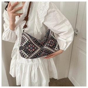 Close-up of geometric ethnic embroidery on a canvas bag with brown leather knotted strap