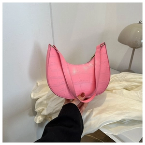 Pink croc-embossed crescent moon underarm bag held by hand in a modern interior