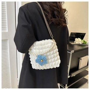Detail of white bubble texture tote bag with pearl handle and plush flower pendant