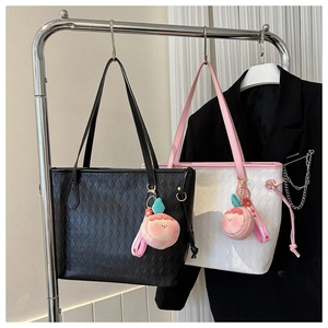 Close-up of quilted tote bags in black and pink with cute plush peach charms