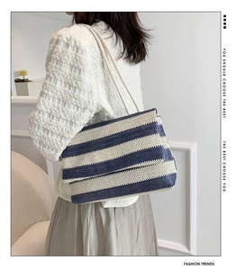 Detail of blue and white striped woven tote bag featuring a textured flap and rope straps