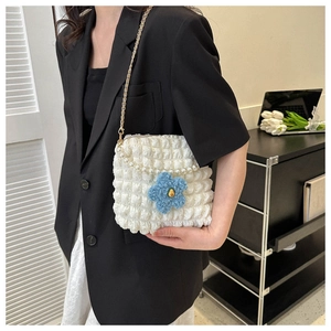 Detailed view of white bubble fabric bag with pearl handle and blue flower charm