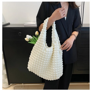 Detail of white popcorn textured fabric tote bag carried by model in black suit