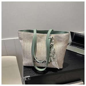 Détail du sac cabas en paille tressée avec anses vertes et foulard décoratif