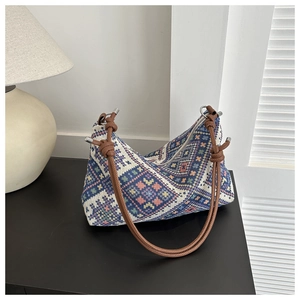 Close-up of geometric ethnic woven tote bag with brown cord handles on a black surface