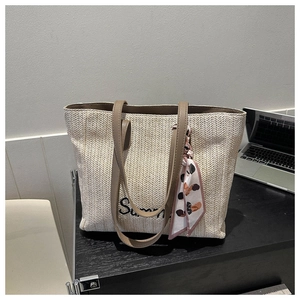 Détail du cabas en paille beige avec broderie Summer et foulard rose décoratif