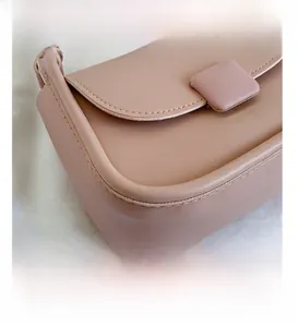 Détail montrant les coutures précises et la boucle carrée rose sur le sac minimaliste