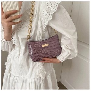 Detail of purple croc-effect baguette bag featuring chunky gold chain and metal hardware