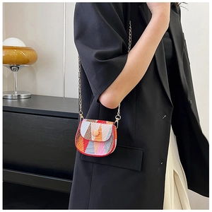 Detail of colorful geometric mini crossbody bag with golden chain strap on a model