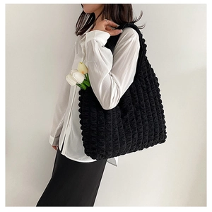 Close-up of black bubble textured tote bag carried by model for a casual fashion look
