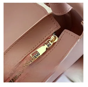 Détail d'une fermeture éclair en métal doré sur un sac en cuir rose texturé