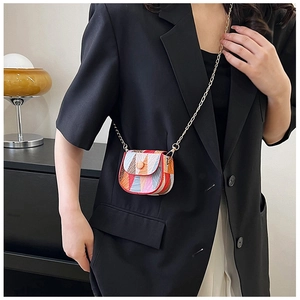 Detail of a mini crossbody bag with abstract color stripe pattern and gold chain strap