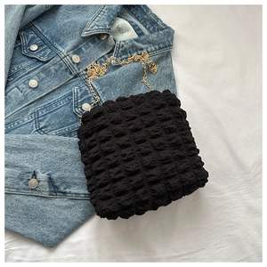 Detail of black bubble textured fabric with golden metal chain strap on minimalist tote bag