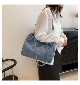 Detail of grey-blue washed denim tote bag featuring metallic rings and fashion logo