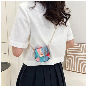 Detailed shot of a mini geometric color-block handbag with a delicate gold chain strap