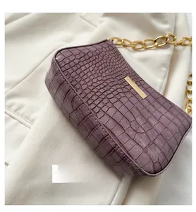 Detailed side view of purple crocodile texture handbag with wide base and gold chain strap