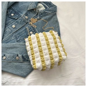 Detail of yellow and white striped bubble tote bag with gold chain on denim