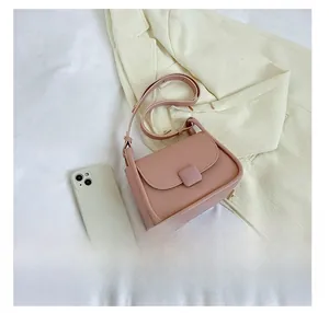 Sac à bandoulière rose en cuir PU avec texture fine et sangle réglable à côté d'un téléphone