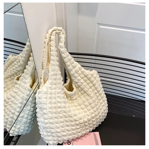 Macro detail of creamy white popcorn fabric handbag with textured 3D flower pattern
