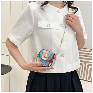 Detail view of mini patchwork crossbody bag with gold chain strap and red round buckle