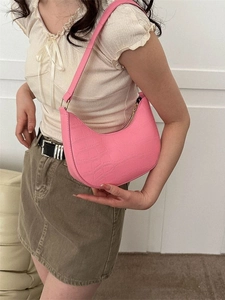 Pink crocodile pattern crescent hobo shoulder bag worn by a fashion model indoors