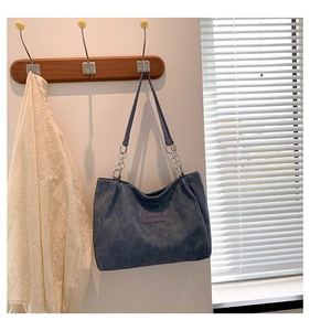 Detail of blue-grey tote bag with silver chain strap and vintage canvas texture