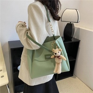 Light green leather tote bag with chain strap and teddy bear charm for daily commute