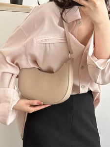 Chic beige crocodile pattern crescent bag worn as a shoulder bag for stylish women