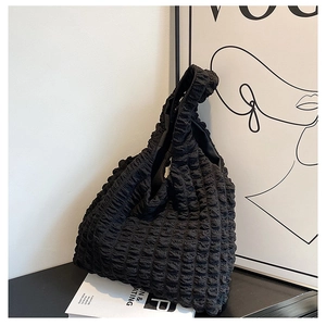 Close-up of black bubble textured fabric and wide shoulder strap on a chic hobo tote bag