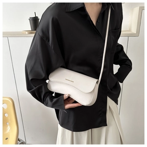 Chic cream white crossbody bag with gold text detail worn over a black shirt