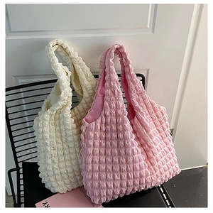 Detailed shot of pink and cream popcorn texture tote bags on a minimal chair