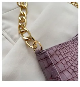 Close-up of luxury purple crocodile embossed leather bag with thick gold metal chain links