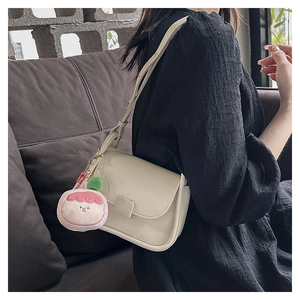 Détail du sac à rabat en similicuir blanc crème avec pendentif en peluche pêche rose